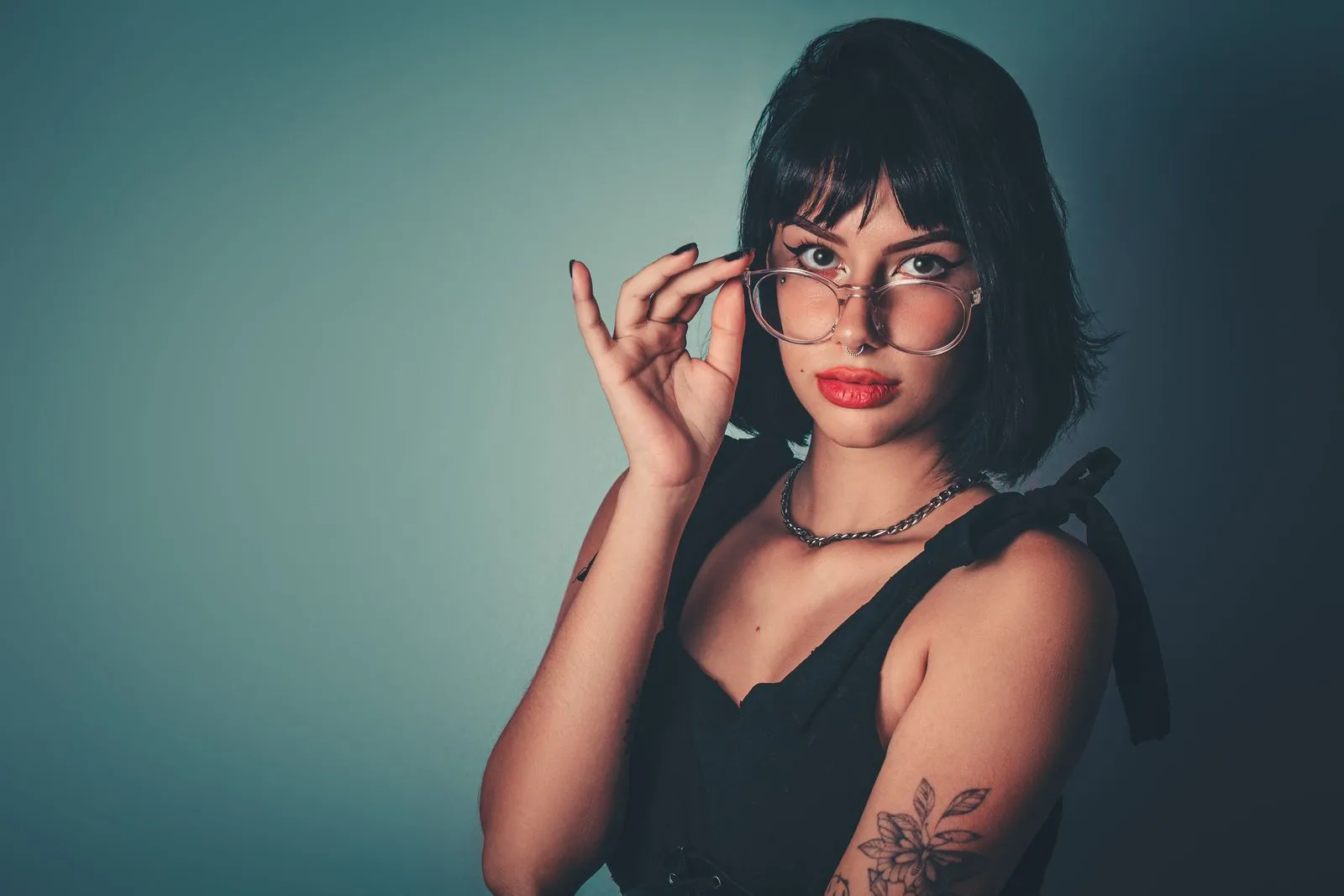 Stylish portrait of a woman wearing eyeglasses and showing a floral tattoo.